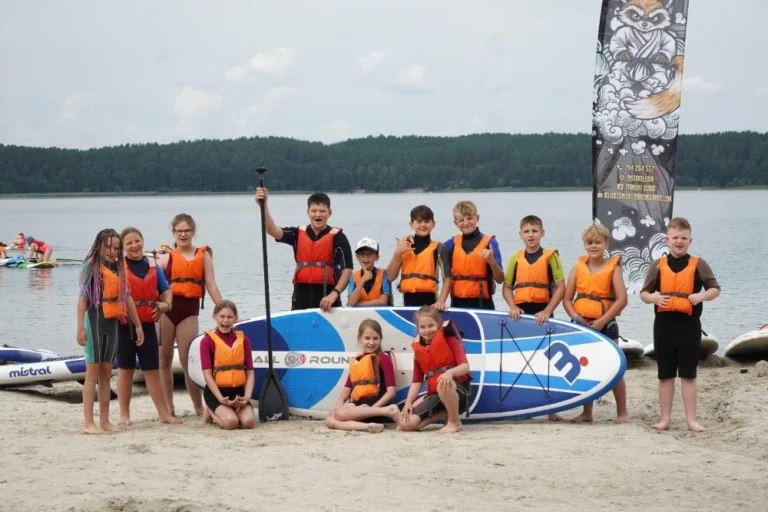 dzieci w grupie przy desce d windsurfingu